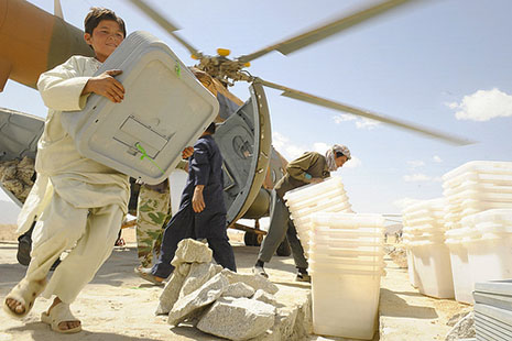 Above: A local boy helps unload ballot materials from an Mi-17 helicopter in the Jaghuri, Afghanistan, for the 18 September elections. Many of the Hazara people who have claimed asylum in Australia were born in this district; those who remain experienced significant difficulties casting a vote. ISAF photo/ Joseph Swafford