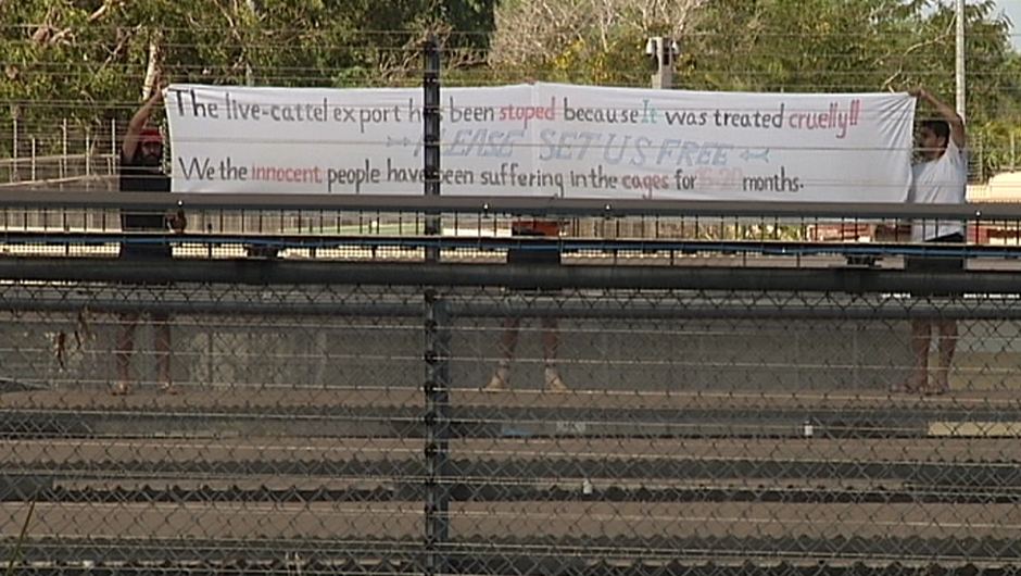 PHOTO: Protestors wave a banner at the Darwin immigration detention centre. (ABC TV)